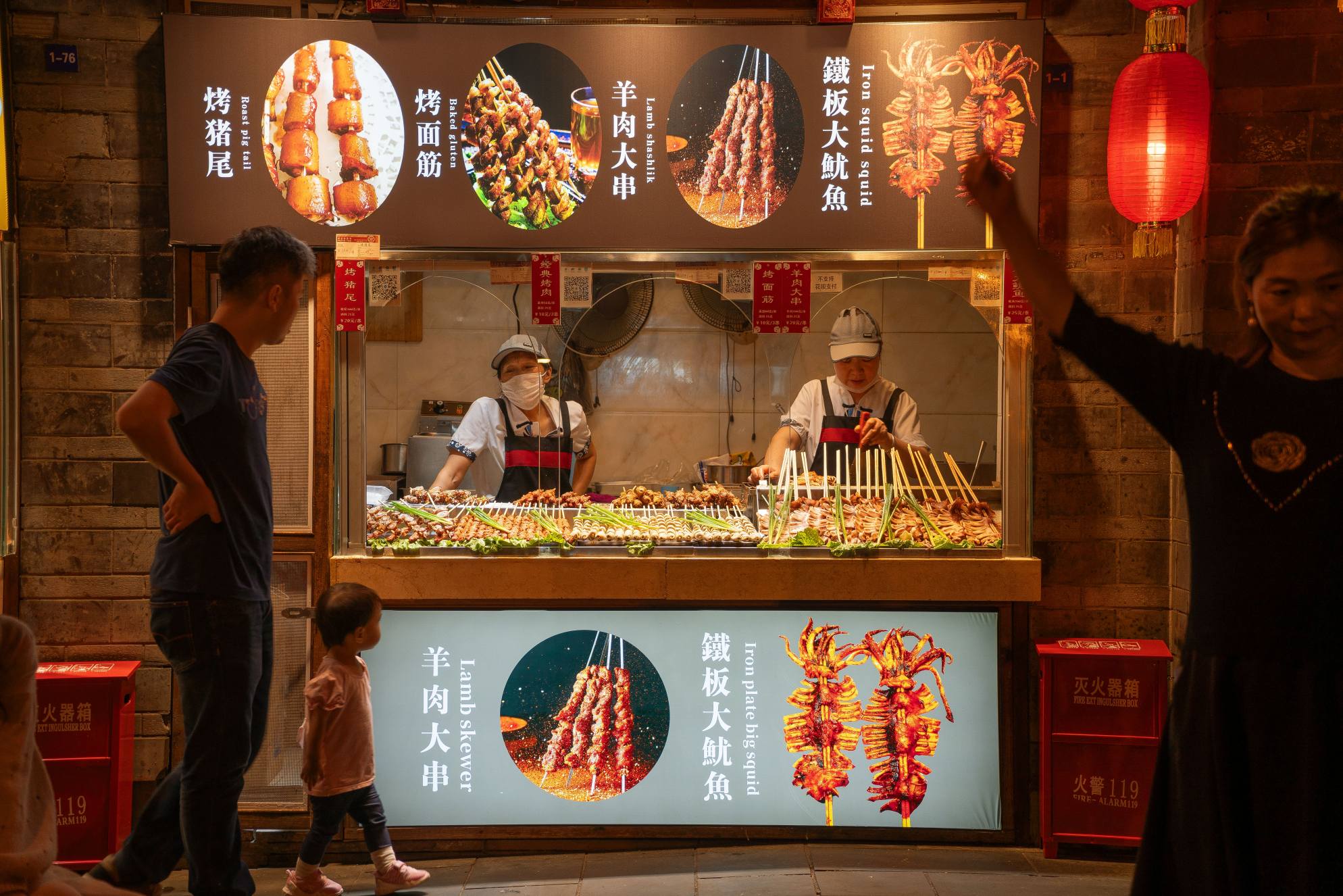 Street food skewers grilling over charcoal in a night market, China